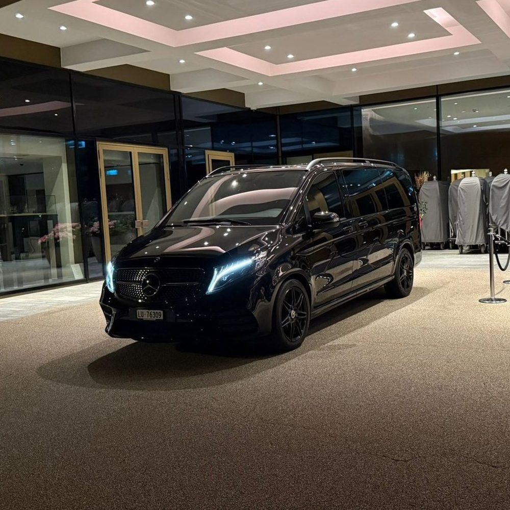 Schwarze Mercedes V-Klasse von Luzerner Taxi abends vor einem beleuchteten Hoteleingang